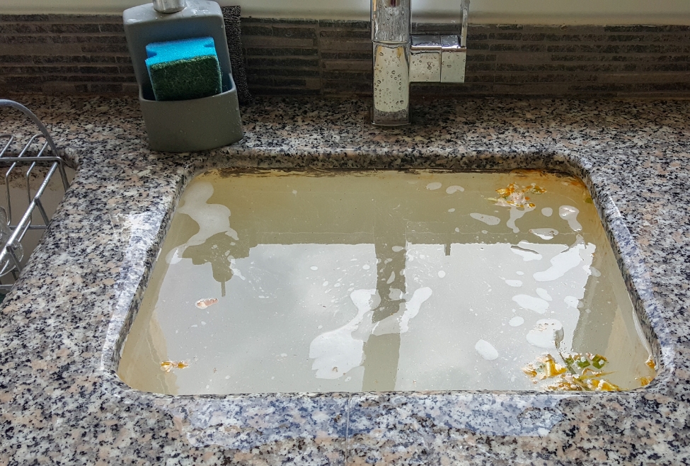 Kitchen sink filled with standing water due to slow drainage, illustrating why is my drain slow but not clogged, including early-stage pipe buildup, partial blockages, and drainage restriction issues requiring professional drain cleaning services, plumbing inspection, and clog removal solutions by Neighborhood Plumbing. Call us now for help with why is my drain slow but not clogged, slow draining sink causes, why is my sink draining slowly but not clogged, bathtub draining slow but not clogged, shower drain slow but no clog, kitchen sink slow drain issues, early signs of drain blockage, partial drain clog symptoms, plumbing drain flow problems, why is water draining slowly in my sink, clogged pipe symptoms without full blockage, drain buildup removal services, grease buildup in pipes solution, hair clog drain slow drainage, sewer line partial blockage signs, main drain slow drainage issues, professional drain cleaning services, hydro jetting drain cleaning, drain inspection services, plumbing clog removal services, emergency drain cleaning near me, drain cleaning near me, plumber for slow drain near me, plumbing services near me, drain unclogging services near me, sewer inspection near me, kitchen drain cleaning near me, bathroom drain cleaning near me.